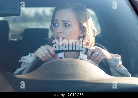 Frau fährt ihr Auto zum ersten Mal, versucht einen Autounfall zu vermeiden, ist sehr nervös und ängstlich, sorgt sich, klammert sich fest am Rad. Unerfahrenwerden Stockfoto