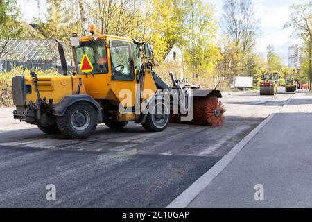 Traktor mit Spinnbürste Reinigung neu gelegt Asphalt. Rekonstruktion und Reparatur der Straße, der städtischen Arbeit. Stockfoto