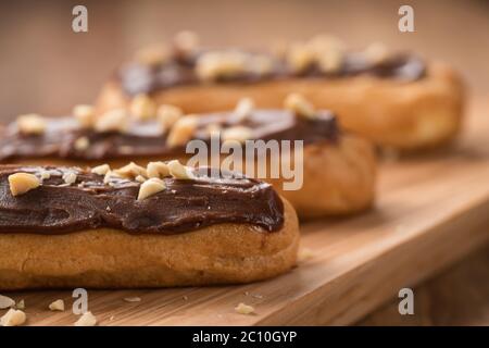 französische Eclairs mit Choclate-Top und Haselnüssen Nahaufnahme Stockfoto