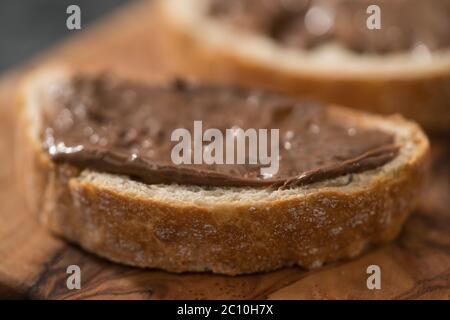 Ciabatta Scheiben mit Schokoladenüberzug auf Olivenholzplatte Stockfoto