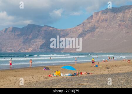 Famara Beach, beliebter Surfstrand an der Küste von Lanzarote. Kanarische Inseln. Spanien. Sanddünen und Menschen am Strand Stockfoto