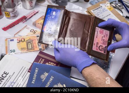 Polizei expert Prüfung der amerikanischen Pass und Geldbeutel ein Beweis Tasche in kriminalistische Labor, konzeptionelle Bild Stockfoto