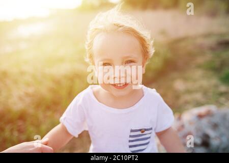 Porträt eines hübschen kleinen blonden Jungen in einer Landschaft unter sanfter Sonne Stockfoto