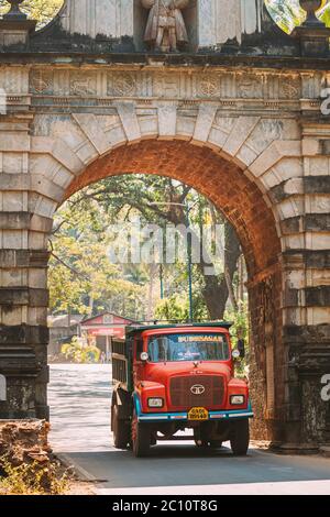 Old Goa, Indien. Red Truck durch den Arch des alten Viceroy. Berühmte Vasco Da Gama Gate Landmark Und Historisches Erbe.Straße In Sonnigen Tag Stockfoto