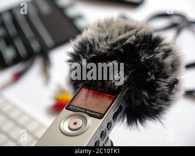 Nehmen Sie mit einer toten Katze im Studio bei Tageslicht Audio im Inneren auf einem Zoom h1 Recorder auf. Im Hintergrund sind Elemente wie Clapperboard, Tastatur, Kabel, Kabel, 3.5, Mini-Buchse zu sehen. Sie können dieses Foto in jedem Projekt verwenden, das mit Tonaufnahmen, Podcasts, Tonstudios, Interviews zusammenhängt Stockfoto