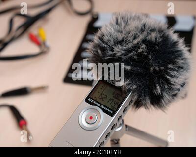 Nehmen Sie mit einer toten Katze im Studio bei Tageslicht Audio im Inneren auf einem Zoom h1 Recorder auf. Im Hintergrund sind Elemente wie Clapperboard, Tastatur, Kabel, Kabel, 3.5, Mini-Buchse zu sehen. Sie können dieses Foto in jedem Projekt verwenden, das mit Tonaufnahmen, Podcasts, Tonstudios, Interviews zusammenhängt Stockfoto