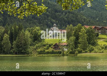 Panoramablick über den Weissensee bei Füssen im Landkreis Ostallgäu bis zur Kirche St. Nikolaus in Oberkirch. Stockfoto