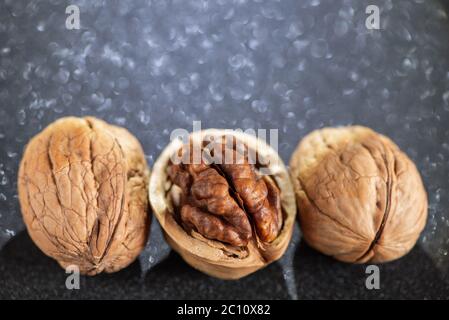 Drei frische leckere Walnüsse mit schönem Bokeh auf schwarzem Hintergrund. Stockfoto