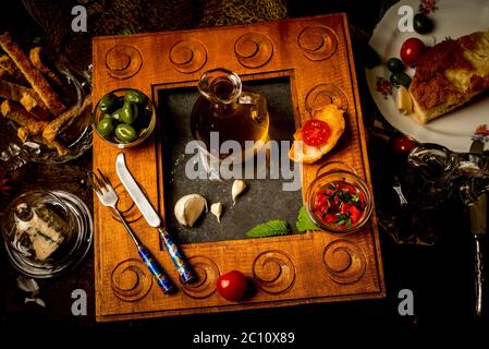 Natives Olivenöl extra, zuerst kalt gepresst, in einem Glas umgeben von Bio-Lebensmitteln in einer alten Holzküche Stockfoto