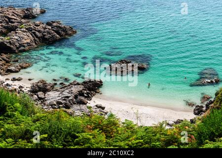 Versteckte Bucht in Finisterre an einem späten Sommernachmittag in Galicien, Spanien, mit zufälligen Badegäste im Wasser. Stockfoto