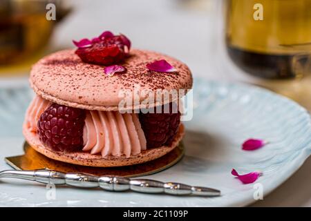 Rosa Himbeer Macaron Kekse auf blauem Teller. Teestunde. Blauer Tabellenhintergrund. Draufsicht. Stockfoto