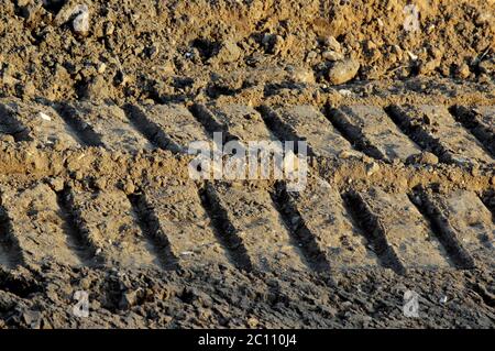 Radspuren im Schlamm, Detail Fußabdrücke Planierraupe in der Baustraße Stockfoto