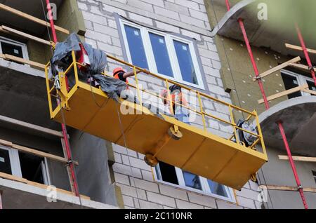 Bau unterbrochen Wiege mit Arbeitern auf einem neu gebauten Hochhaus Stockfoto