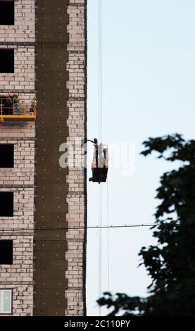 Bau unterbrochen Wiege mit Arbeiter auf einer neu gebauten Hochhaus Stockfoto