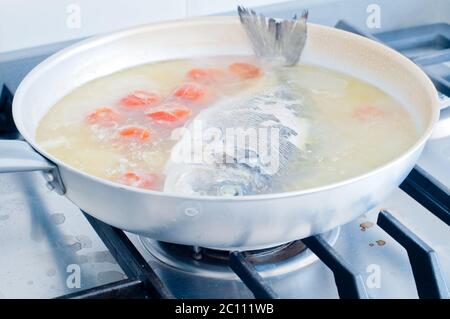 Fisch Goldbrasse in verrückt Wasser gekocht, Typisches Rezept von Süditalien mit Meerwasser, Tomaten, Zwiebeln und Knoblauch Stockfoto