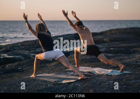Fitness, Sport und Lifestyle-Konzept - Paar macht Yoga-Übungen am Strand Stockfoto