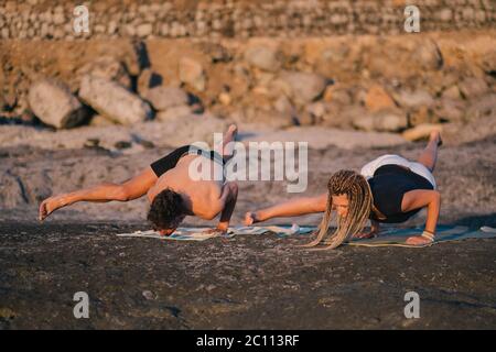 Fitness, Sport und Lifestyle-Konzept - Paar macht Yoga-Übungen am Strand Stockfoto
