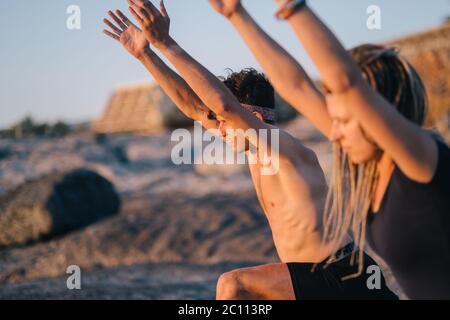 Fitness, Sport und Lifestyle-Konzept - Paar macht Yoga-Übungen am Strand Stockfoto