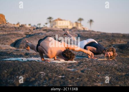 Fitness, Sport und Lifestyle-Konzept - Paar macht Yoga-Übungen am Strand Stockfoto