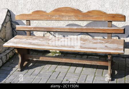 Alte hölzerne leere Bank, die auf einem offenen gepflasterten Bereich steht Stockfoto