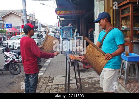 Satay Verkäufer fanning satay, das gegrillt wird. Satay ist südostasiatisches Gericht, das aus kleinen Fleischstücken besteht, die auf einem Spieß gegrillt werden Stockfoto