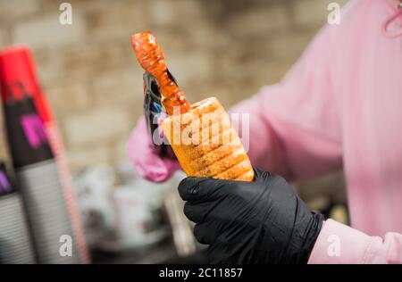 Barkeeper Putting Grill Wurst in Rolle französisch Hot Dog mit Sauce Stockfoto