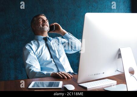 Selbstbewusster lächelnder Geschäftsmann, der einen Anruf auf seinem Smartphone hat. Stockfoto