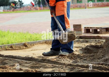 Maurer Sand werfen Schaufeln für die Verlegung Pflasterplatten auf dem Stadtplatz Stockfoto