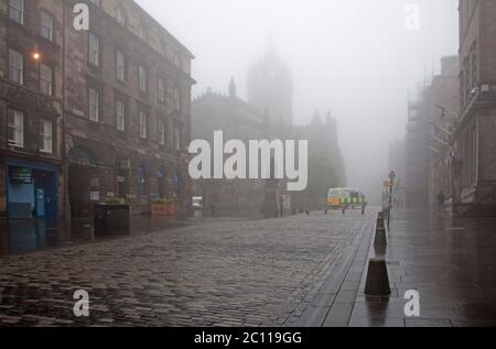 Royal Mile, Edinburgh, Schottland, Großbritannien. 13. Juni 2020. Die High Street, umgeben von dichtem Nebel, an der Stelle, wo in normalen Zeiten sogar mit dieser Art von Wetter Straßenkünstler von Einheimischen und Touristen umgeben sein würden, die die Menge mit ihren Fähigkeiten unterhalten, aber aufgrund der Covid-19 Coronavirus-Sperre in Phase 1 sind nur wenige Leute unterwegs. Eine vernünftige Polizeipräsenz in der Stadt. Stockfoto