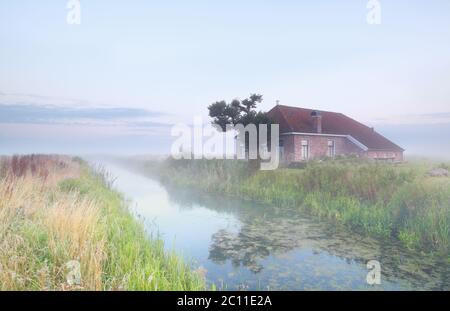 Gemütliches Haus in nebligen Morgen am Fluss Stockfoto