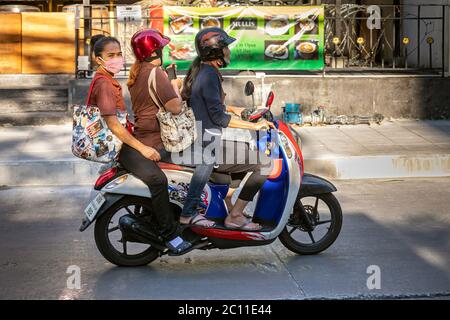 Drei Menschen mit Facemarks auf dem Motorrad während der Covid-Pandemie, Bangkok, Thailand Stockfoto