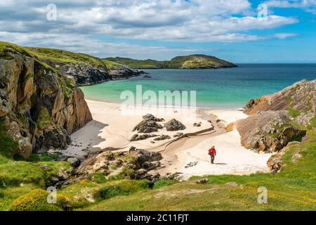 ACHMELVICH BAY UND STRAND SUTHERLAND HIGHLANDS SCHOTTLAND BLAUER HIMMEL MIT WOLKEN TÜRKISFARBENES MEER UND EIN EINFARBIGER WALKER Stockfoto