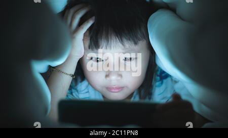 Auge Nahaufnahme Little Girl sind gerade Video in Tablet auf dem Bett in der Nacht Licht blinkt vom Bildschirm reflektiert, Kinder mit Spielen mit sucht Stockfoto
