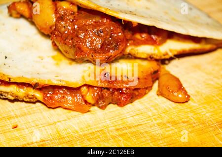 Quesadilla mit Hackfleisch, Wurst, roten Bohnen, Mais, Zwiebeln und Tomatensauce. Ein traditionelles mexikanisches Essen. Nahaufnahme Stockfoto