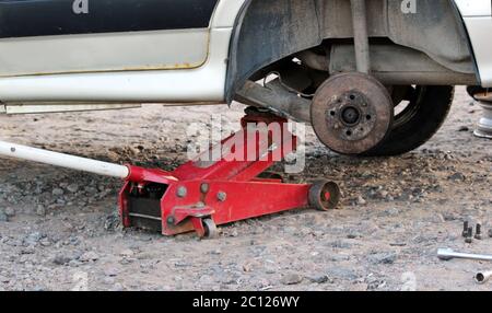 Auto in der Garage, Hydraulischer Wagenheber heben ein Auto, Rad ohne Reifen, Schlüssel Cross Straße und vier Muttern Stockfoto