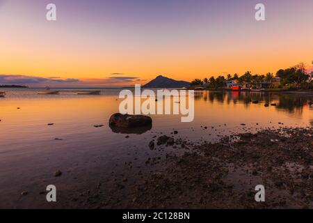 Meer mit Fischerbooten und Stadt bei Sonnenuntergang in Mauritius. Stockfoto