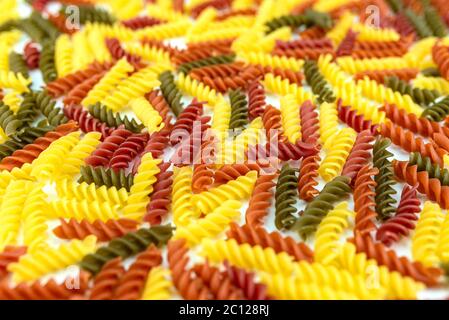 Hintergrund aus vielen bunten Spiral Pasta, abgeschrägte Ansicht, Fokus auf die Mitte, der Rest ist verschwommen. Stockfoto