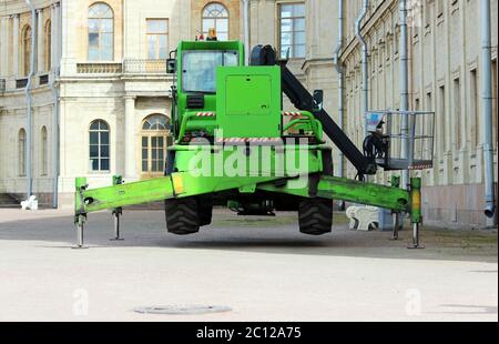 LKW starke Stützen stabilisierende Beine verlängert. Boom hebt Baustoffmaschinen auf dem Dach des Palastes Stockfoto