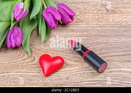 Lippenstift, rote Herzen und Tulpen auf einer hölzernen Hintergrund Stockfoto