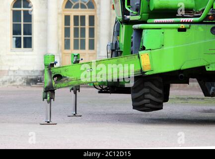 LKW starke Stützen stabilisierende Beine verlängert. Boom hebt Baustoffmaschinen auf dem Dach des Palastes Stockfoto