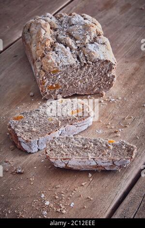 Rustikaler Brotlaib in Aprikosenstückchen auf einem rustikalen Holztisch Stockfoto