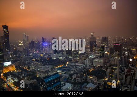 Die erleuchteten Wolkenkratzer der Skyline von Bangkok während des romantischen Sonnenuntergangs in Orange in Thailand Stockfoto