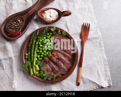 Saftig geröstetes Rindfleisch gehacktes Steak, mit grünen Erbsen, Spargel, auf dem Teller close up Stockfoto