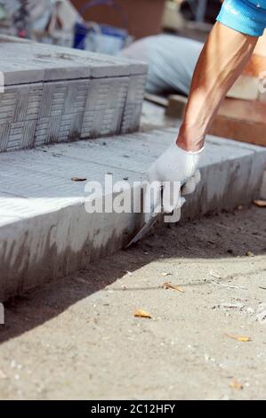 Fliesenleger verarbeitet die Oberfläche für die Verlegung der Steinfliesen auf den Stufen in der Reparatur des Bürogebäudes. Stockfoto