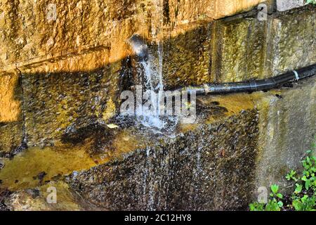 Wasser fließt an einer schmutzigen Wand entlang Stockfoto