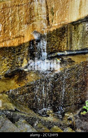 Wasser fließt an einer schmutzigen Wand entlang Stockfoto