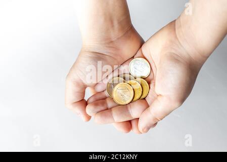 Nahaufnahme Kinderhände halten Euro-Münzen isoliert auf weißem Hintergrund. Taschengeld-Konzept. Stockfoto