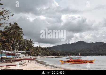Traditionelle philippinische Fischerboote dockten vor einem Sturm an einem Strand in einer Lagune auf der Insel Port Barton Palawan auf den Philippinen an Stockfoto