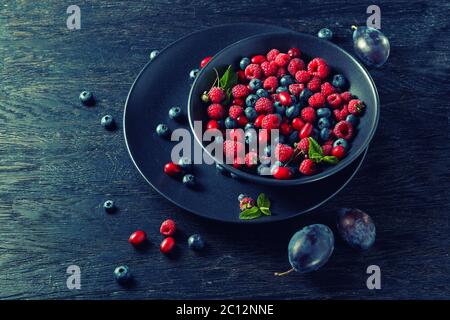 Himbeeren, Blaubeeren, Pflaume und Hartriegel. frische Beeren auf Platte Stockfoto