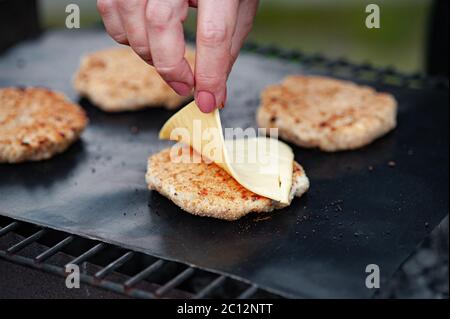 Käse auf ein Kotelet legen. Gegrillter Burger-Kotelet Stockfoto